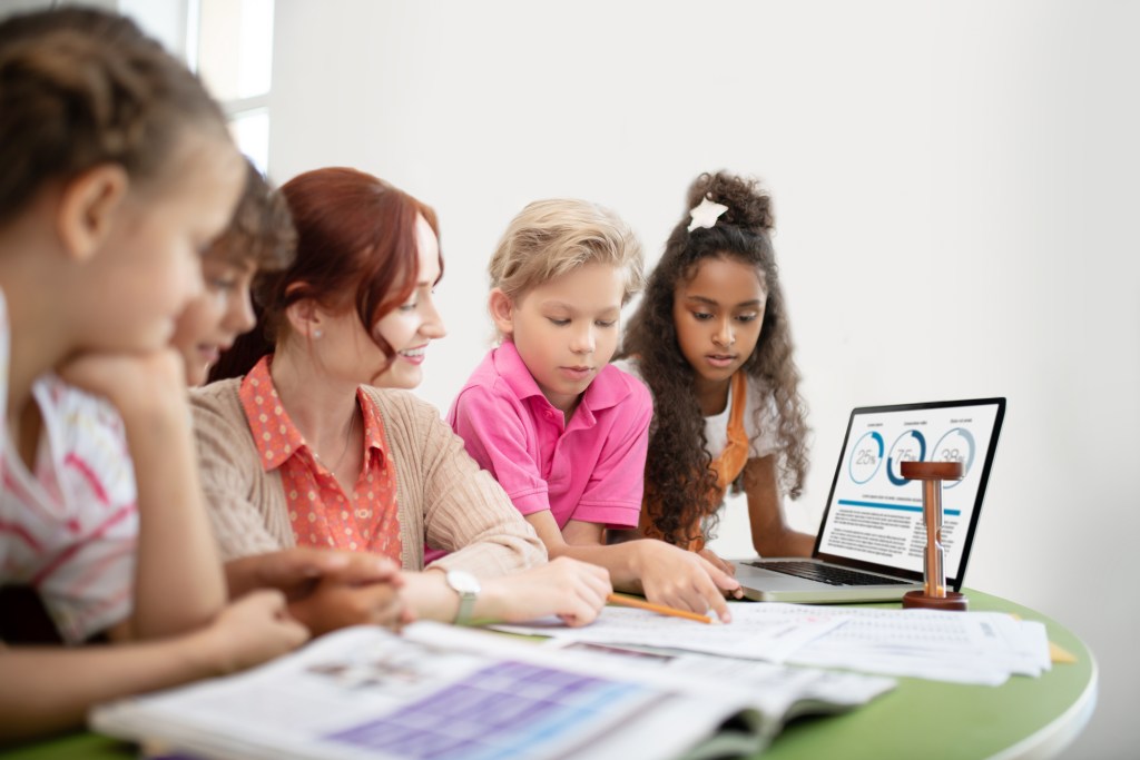 Ferramenta de aprendizagem: o que é, tipos e como escolher? 1 foto professora e alunos em aula com uso de laptop