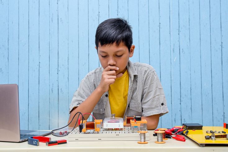 Cultura maker: o que é e como adotá-la na escola 1 Foto de estudante realizando atividade maker na escola com fios, circuitos, motor e computador