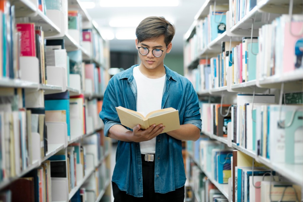 Recomposição de aprendizagem: como reduzir as perdas da pandemia 5 Aluno lendo livro em biblioteca
