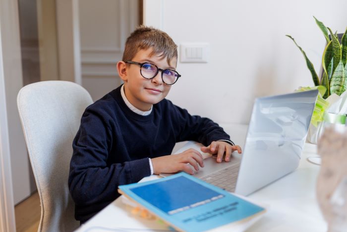 Recomposição de aprendizagem: como reduzir as perdas da pandemia 3 Foto de menino estudando em casa no notebook para recompor aprendizagens.