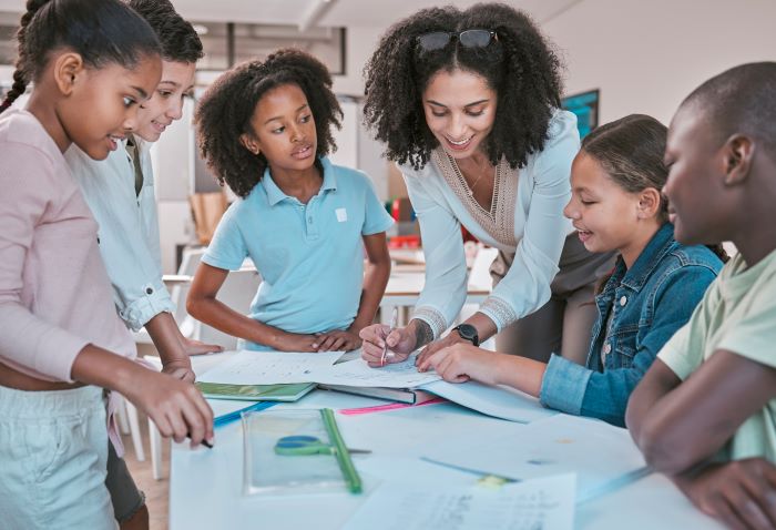 Metodologias ativas de aprendizagem: 12 tipos e como adotá-las 1 Foto de professora revisando projeto elaborado por grupo de estudantes.