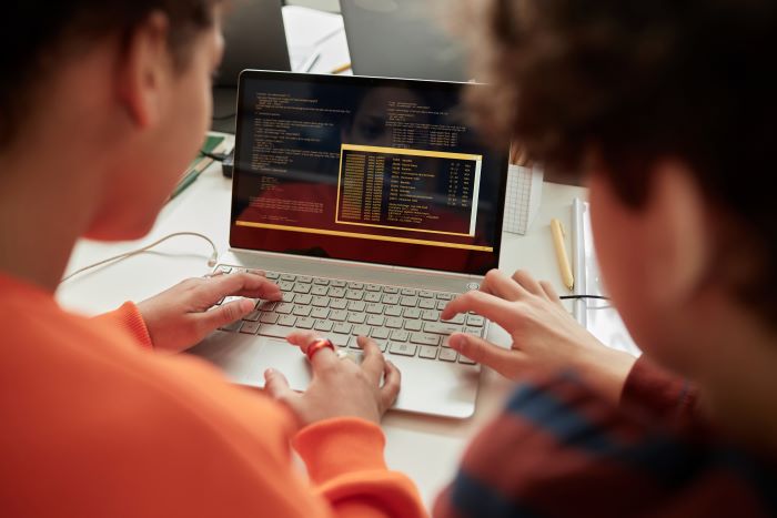 Letramento digital: o que é e como desenvolver na sua escola 1 Estudantes fazendo atividade de programação em notebook.