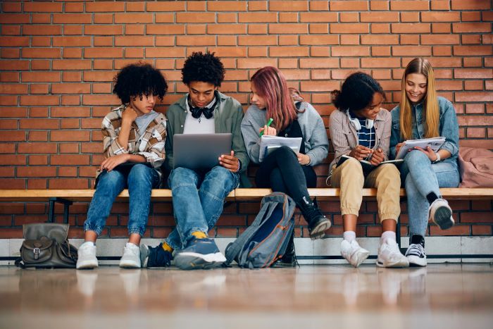 Aprendizagem colaborativa: o que é e quais os benefícios 1 Grupo de alunos estudando juntos no corredor da escola.
