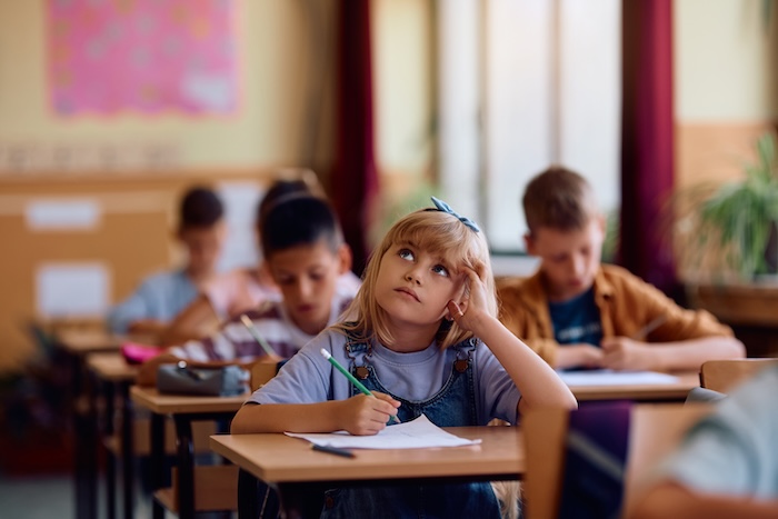 Quais são os tipos de avaliação escolar? 1 aluna pensativa fazendo avaliação escolar