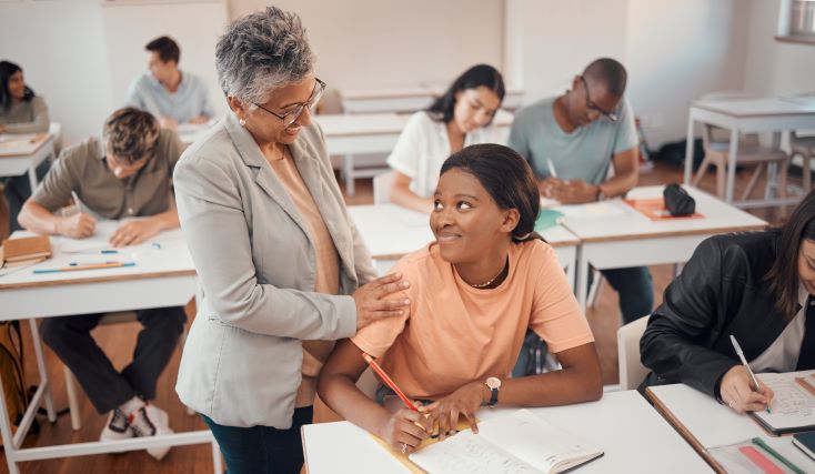 Educação socioemocional: como trabalhar emoções na escola? 2 Foto de diretora escolar conversando com estudante em sala de aula, dando apoio emocional