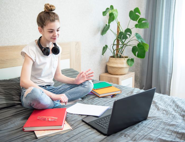4 pilares da educação: quais são e como aplicar 2 Foto de garota estudando em casa com notebook, cadernos e livros