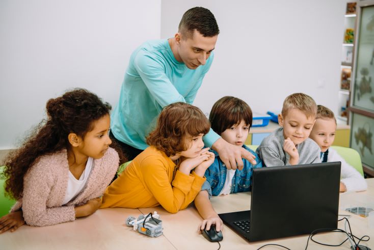 7 passos para organizar o horário escolar da sua escola 1 Foto de professor orientando crianças em aula de programação na escola