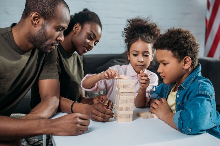 Como aproximar a família da escola e fortalecer a relação de parceria? 2 Texto alternativo: Foto de família fazendo atividade juntos com blocos de madeira