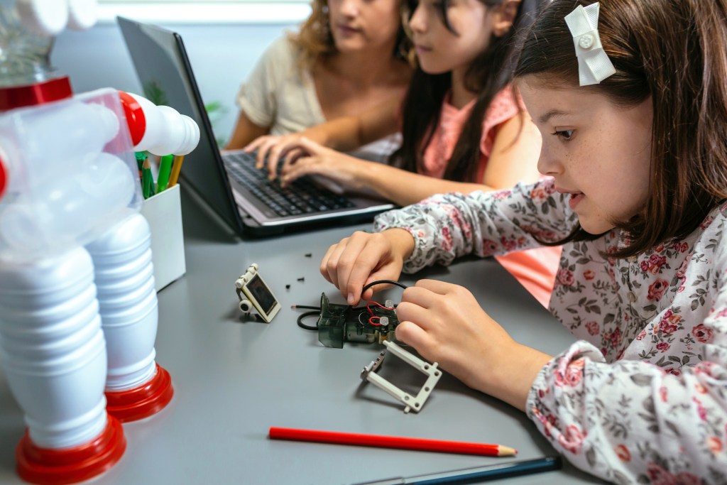 Atividades lúdicas com tecnologia: guia prático para competências digitais na escola 1 Foto criança conectando fio em circuito elétrico na aula de robótica