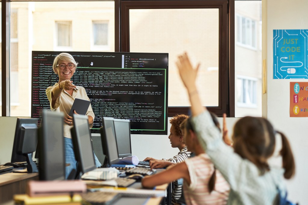 Atividades lúdicas com tecnologia: guia prático para competências digitais na escola 2 Foto crianças e professora em aula de programação na escola