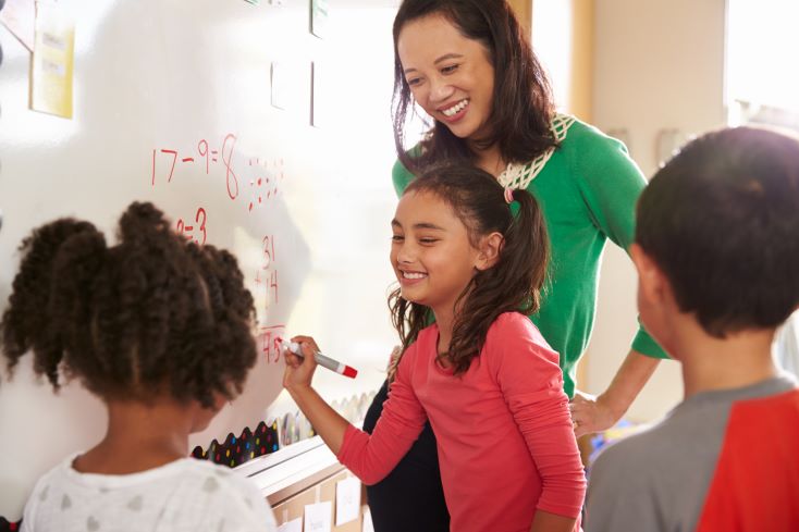 Educação financeira na escola: importância e como fazer 1 Foto de professora orientando alunos em aula de Matemática e educação financeira