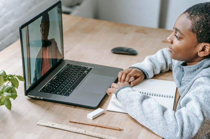 Ensino remoto: como ensinar e avaliar os alunos à distância? 1 Foto de menino assistindo aula online na Educação Básica