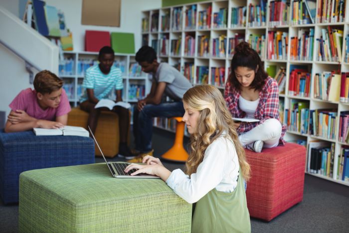 9 passos para organizar uma biblioteca escolar 1 Foto de alunos usando uma biblioteca escolar organizada