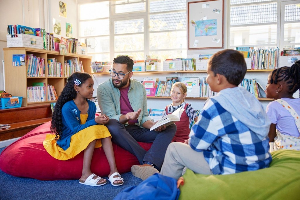 Leitura Infantil: quando começar e quais gêneros escolher? 2 Foto de professor e alunos na biblioteca