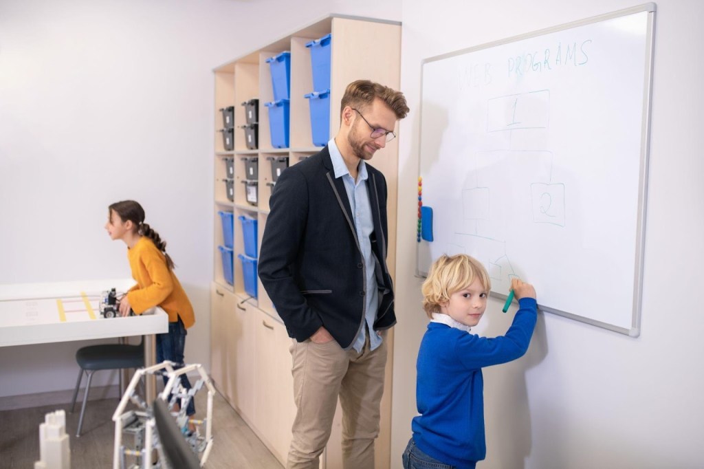 Como a tecnologia pode apoiar crianças autistas no ambiente escolar? 2 Foto de alunos e profissionais de apoio especializado na sala de recursos multifuncionais